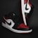 A pair of stylish athletic shoes in black, white, and red colors with distinctive branding. The shoes are positioned against a dark background, showcasing their sleek design and detailed craftsmanship.